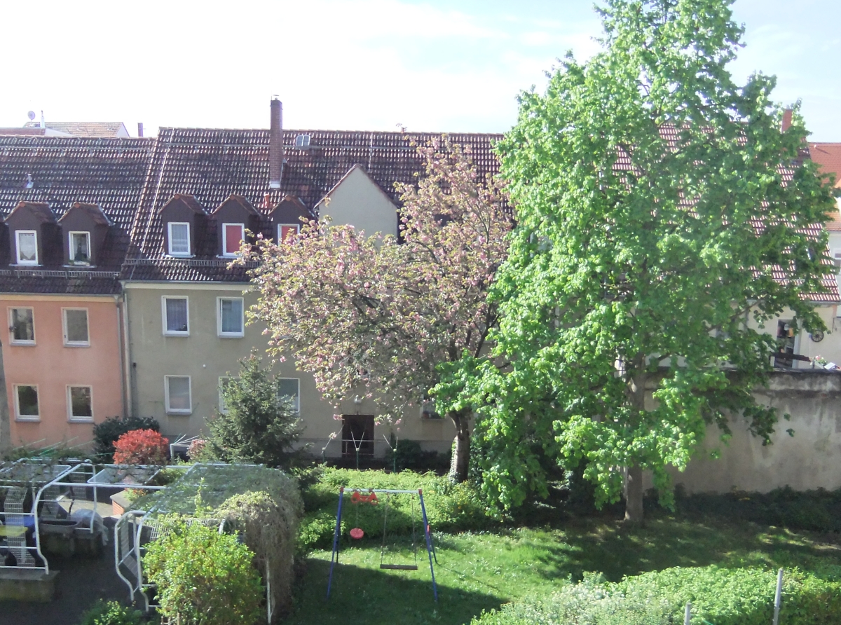 Ansicht eines dreistöckigen sanierten Mehrfamilienhauses vom grünen Innenhof aus